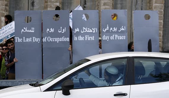 Left-wing Israelis and Palestinians demonstrators hold placards during a demonstration calling for a better future for both people
