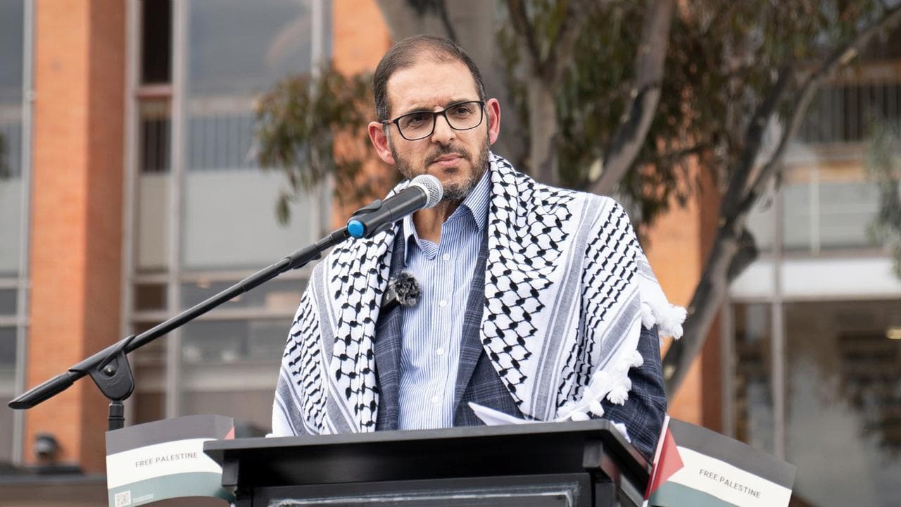 Man wearing keffiyah at a microphone