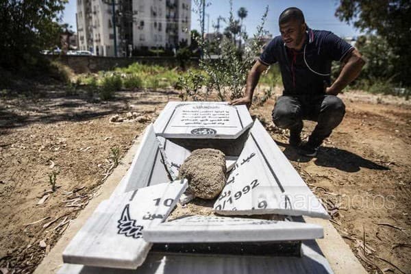 A resident of Lod looks at one of the several vandalised graves in a Muslim cemetery, May 14 (AP/Heidi Levine)