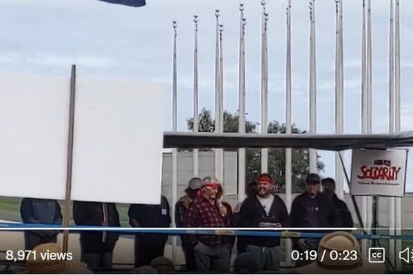 Mark McMurtrie, third from right, with red headband, addresses the rally