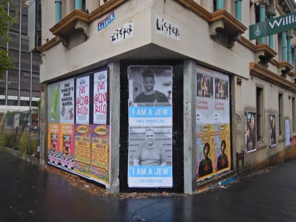 Two posters reading I am a Jew on a busy street.
