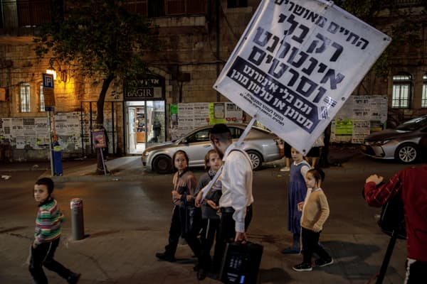 An Orthodox Jew walks through the streets of Mea Shearim, the ultra-Orthodox neighbourhood of Jerusalem, with a sign that reads "Life is happy only without the internet and movies"