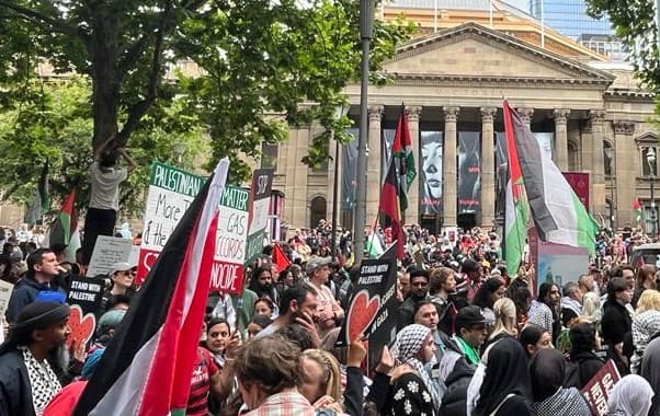 Many people and flags in front of a building with columns