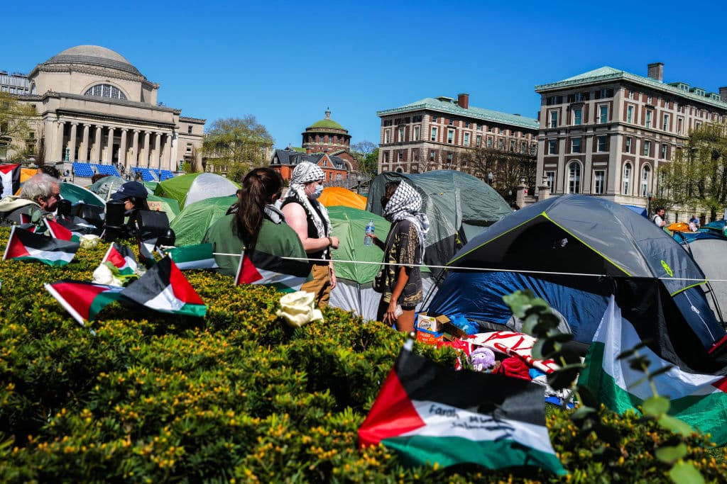 tents, flags, people in keffiyah in front of grand university buildings