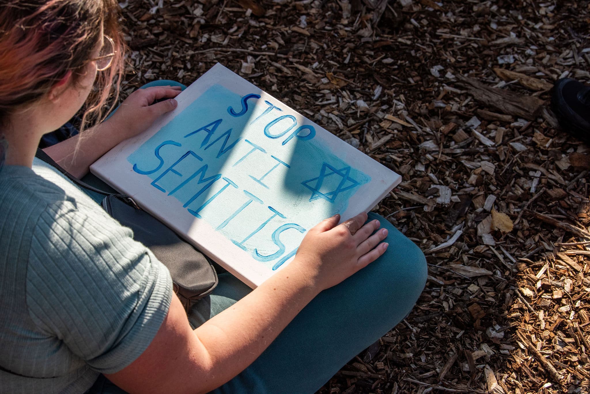 A young girl looking at a sisng reading Stop Anti Semitism