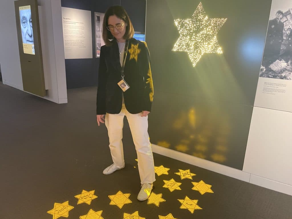 Melbourne Holocaust Museum's Aviva Weinberg demonstrates an interactive display which makes participants "wear" a yellow star (Image: TJI).