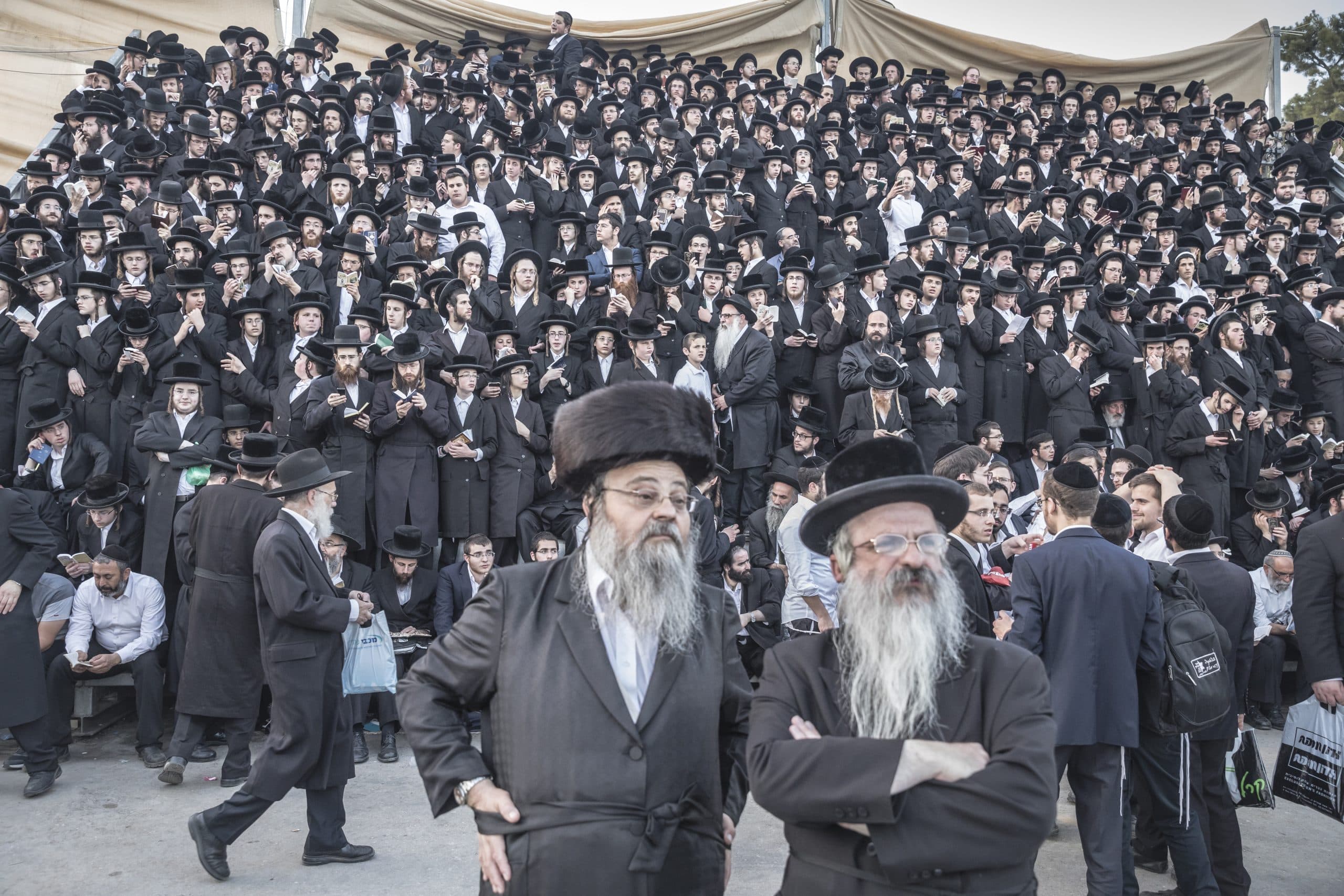 Cowd of bearded men in black hats and coats.