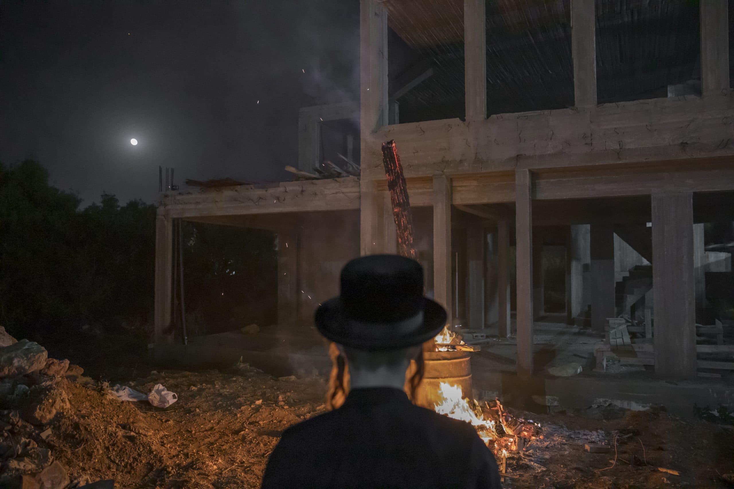 Man in dark hat scene from the back with a fire in front of him