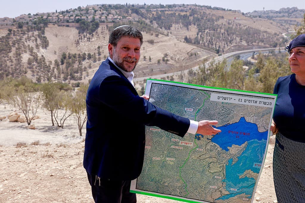 Man with a large map in front of a barren landscape