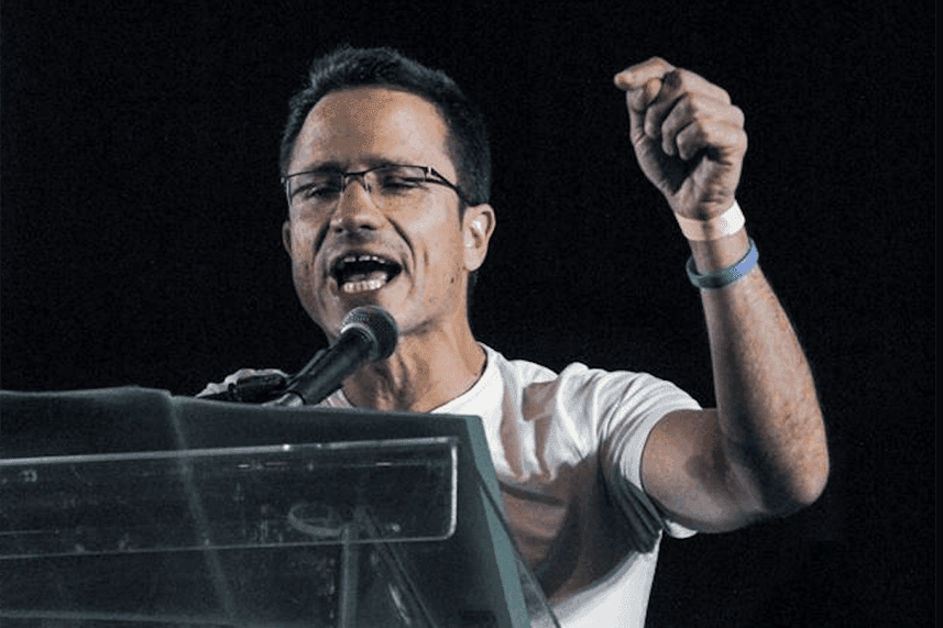 Man speaking into a microphone and gesturing