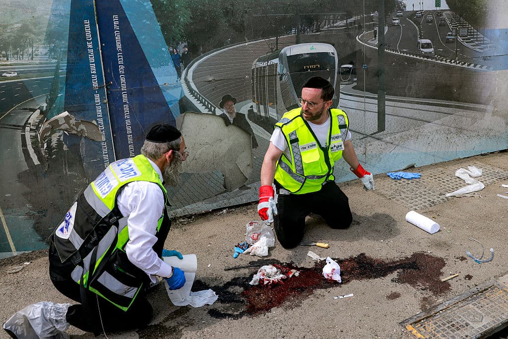 Two men cleaning blood from the street after the Jerusalem terror attack