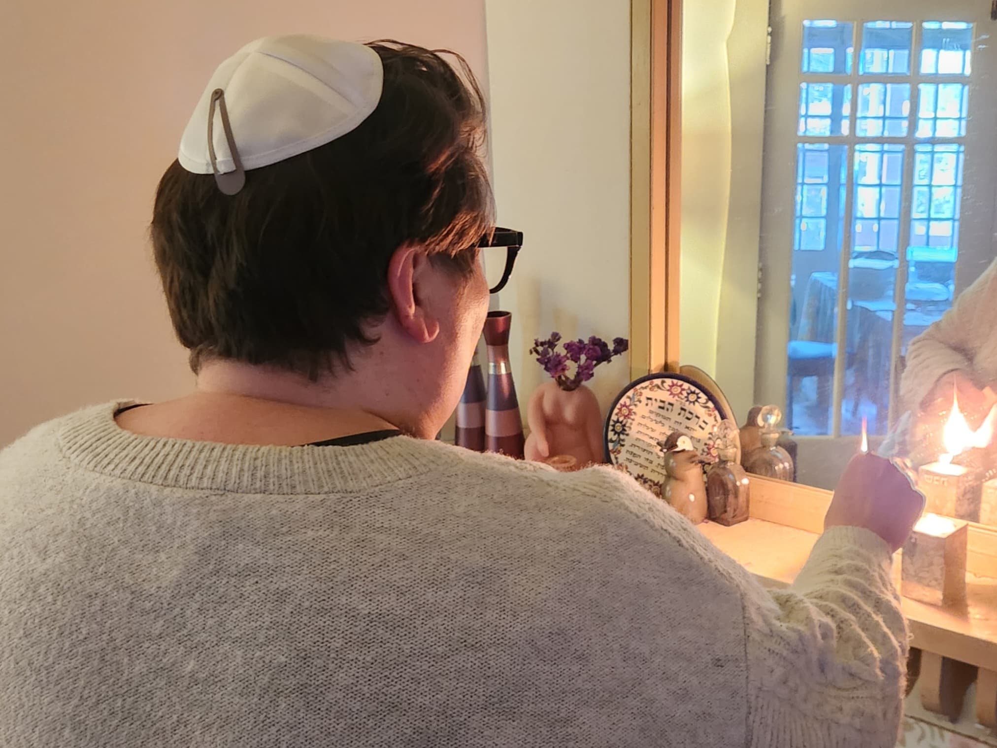 Elizabeth lighting a candle wearing a kippah