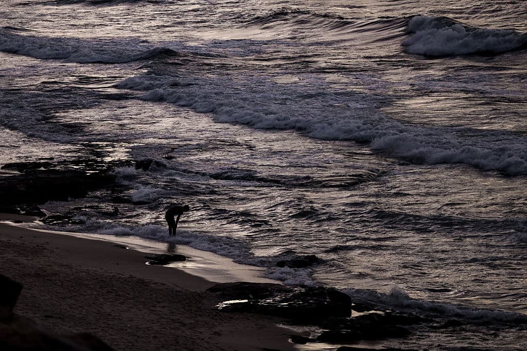 A man on the edge of the sea in the Nuseirat area of Gaza City, where people continue their daily lives despite the continuing war (Khames Alrefi/Anadolu via Getty Images)