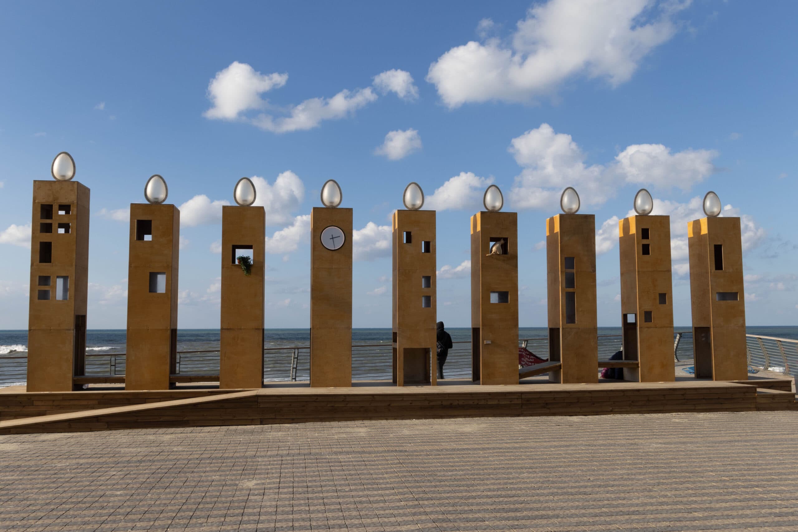 Large wooden structures which look like apartment buildings or towers but form a nine branch candlelablra with lights on top.