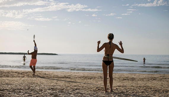 A woman spins a hula hoop around her waist on a beach in Tel Aviv