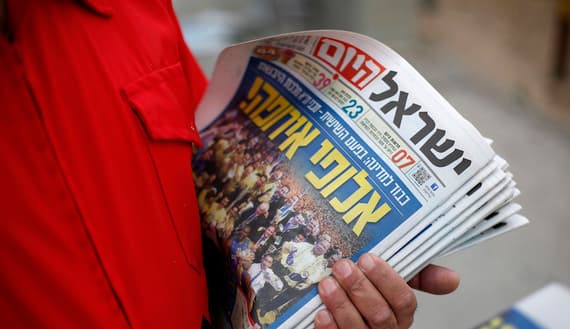An Israeli worker for for the daily newspaper  holds copies of the newspaper as he distributes them in Jerusalem