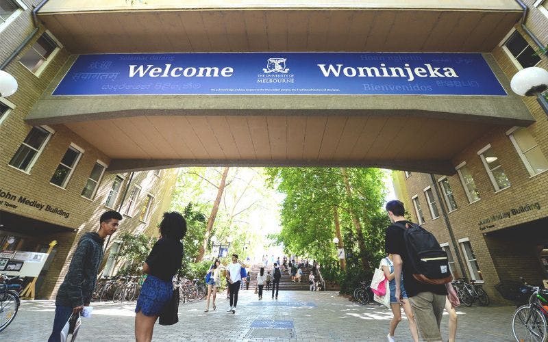 Sign saying Wominjeka and Welcome with univesity logo and students walking underneath