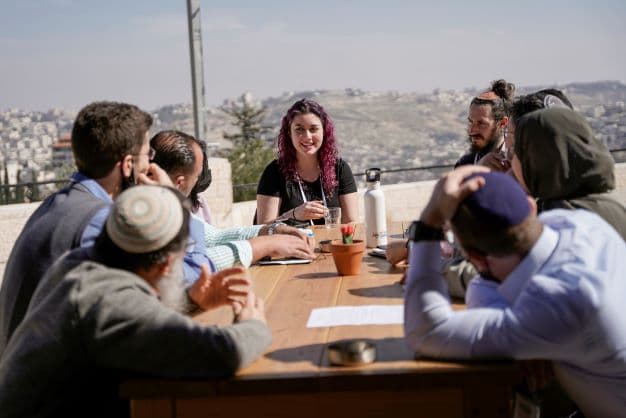 People sitting around a table with Jerusalem in the background