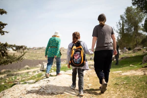 A Hineinu volunteer accompanies a child to school in Tuba (Emily Glick)