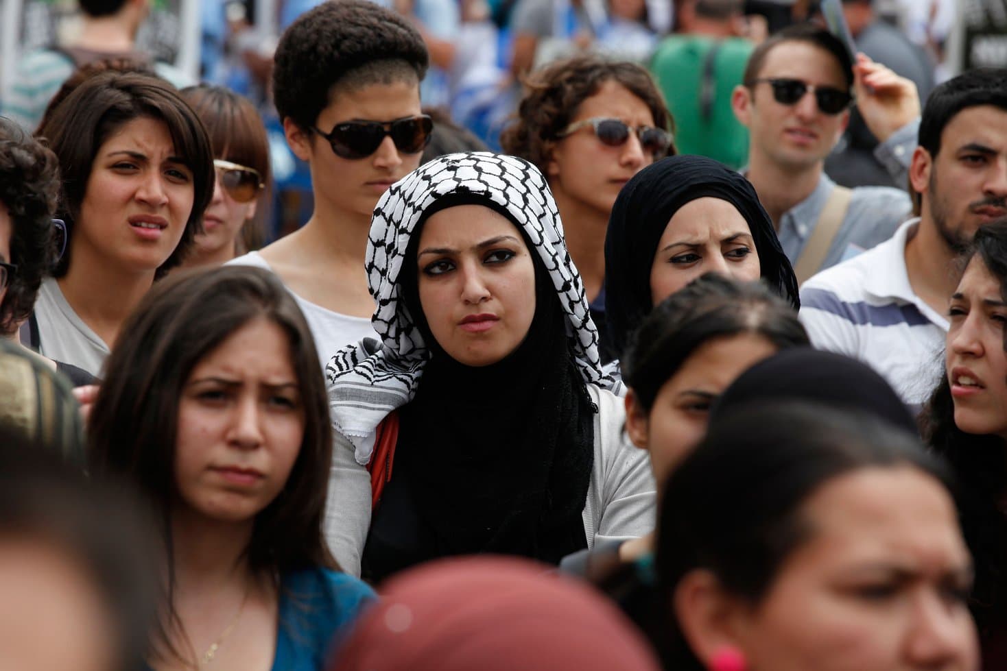 Crowd of students, one wearing a keffiyah