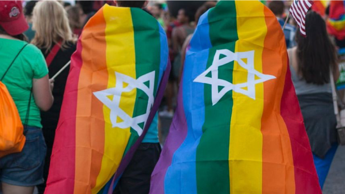 Two people draped in rainbow flags with the Star of David