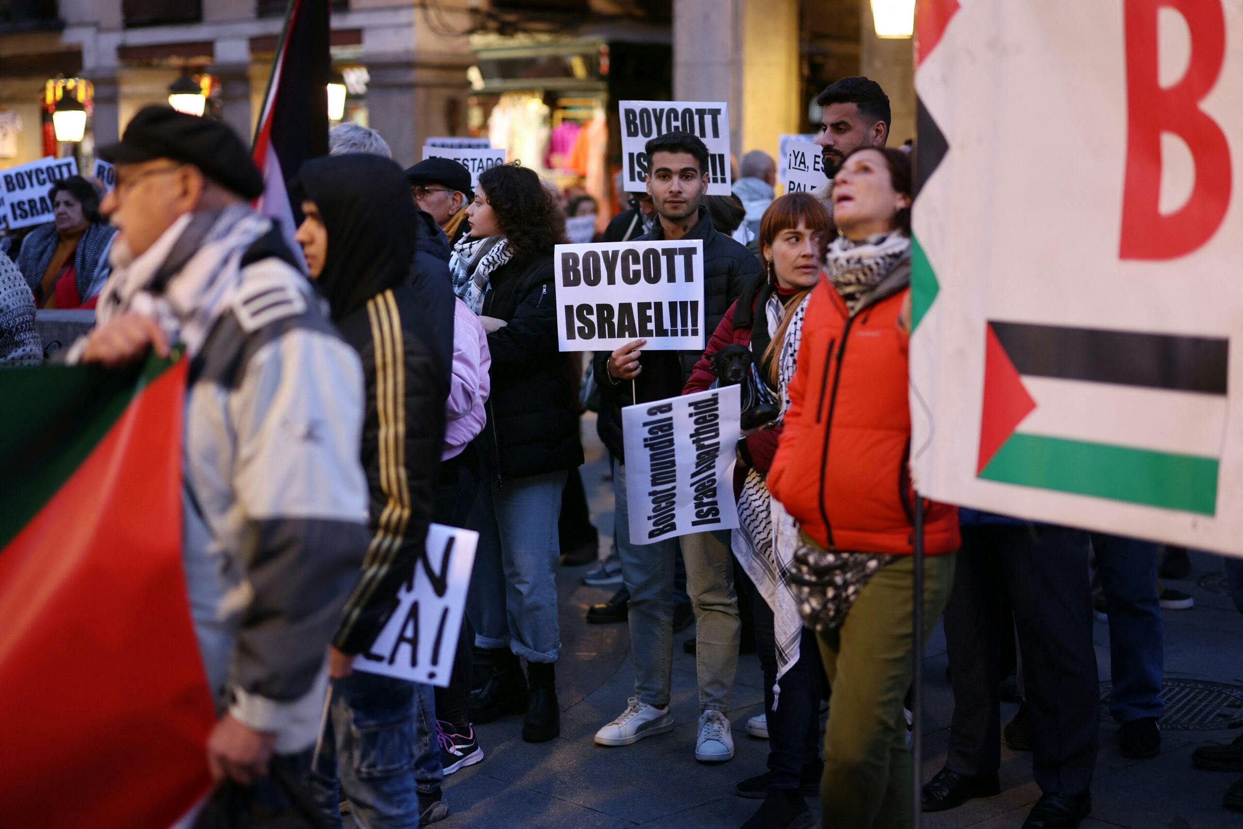 A man holds a boycott israel poster in a pro-Palestinian rally