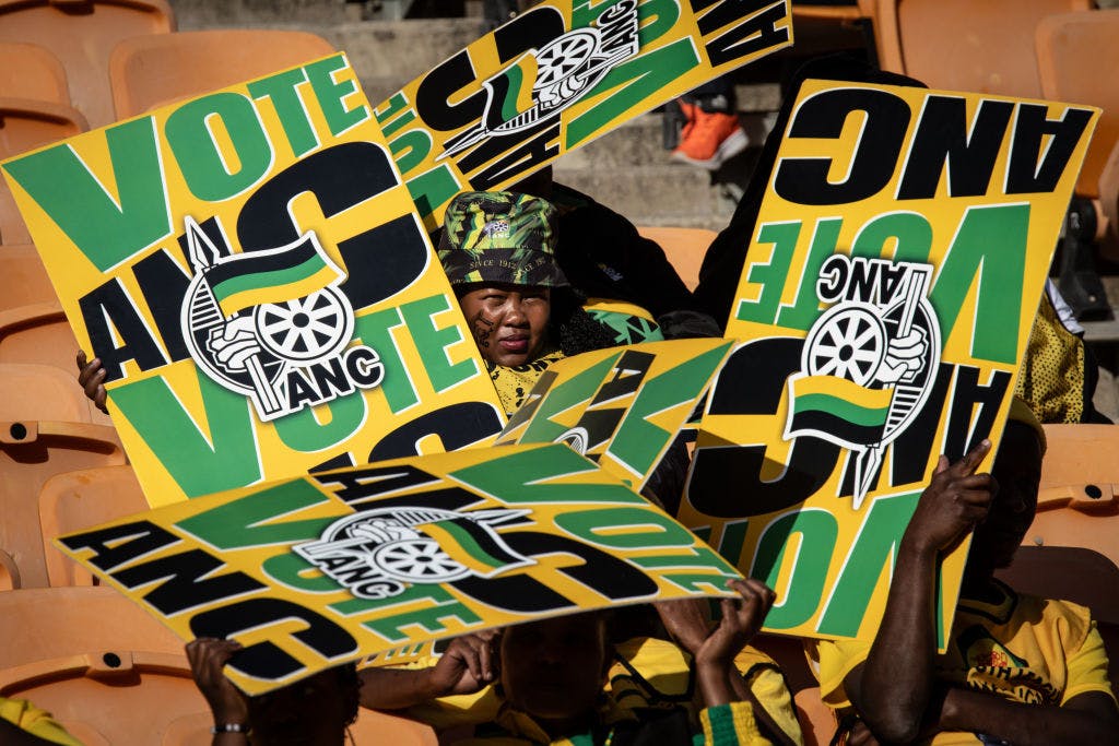 Posters with the words Vote ANC and a person in a camoflauge hat peaking between them