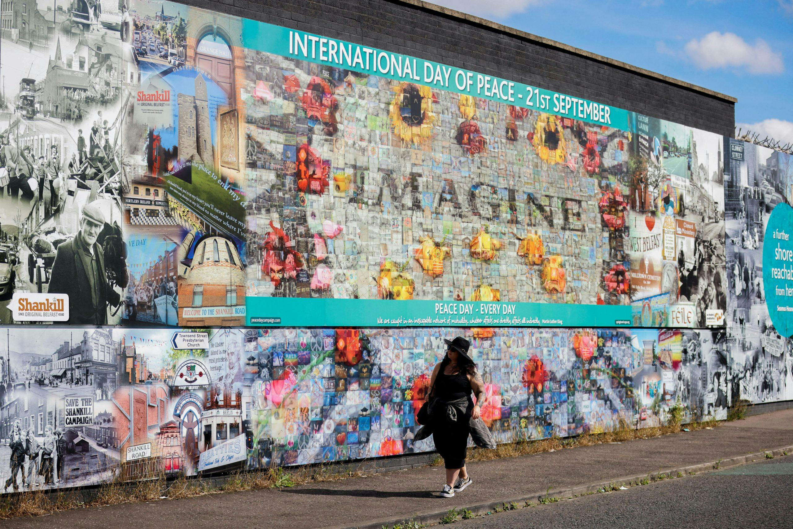 Colourful wall with the word Imagine printed on it and a woman walking past