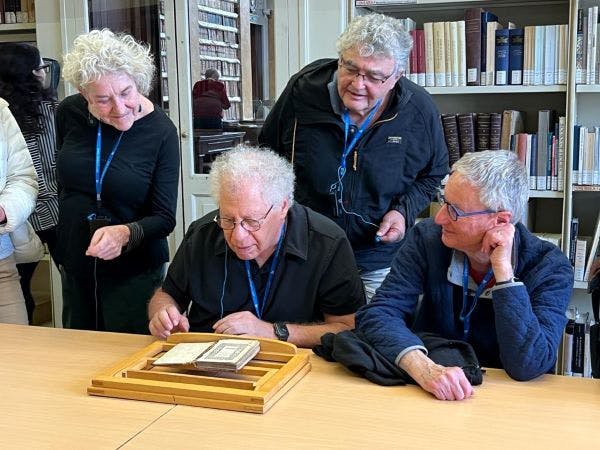 Four people pouring over a small Hebrew book