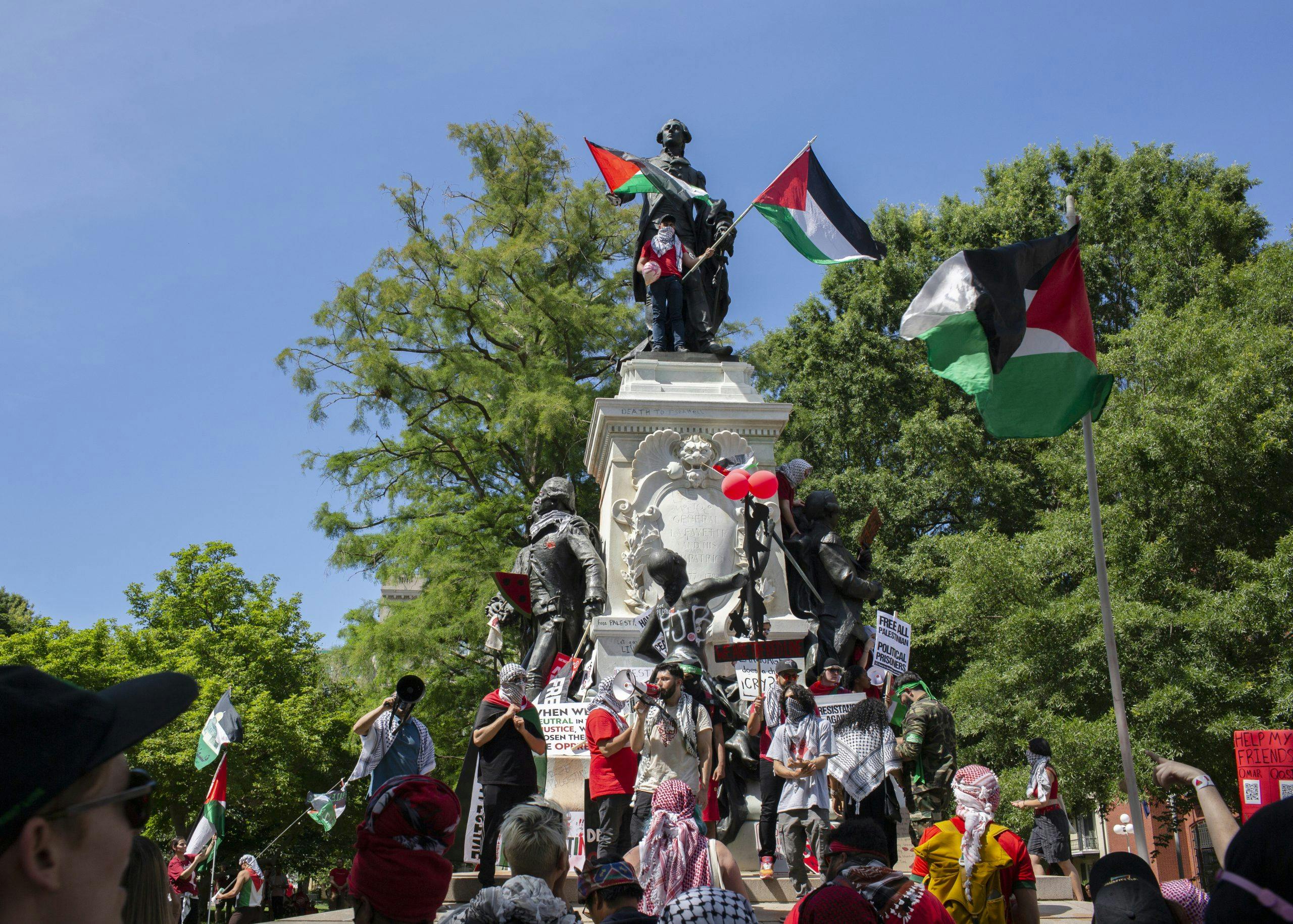 People with Palestinian flags climbing on a statue