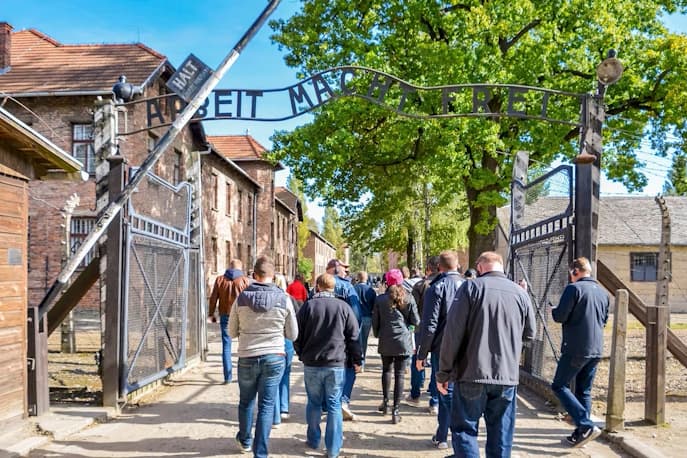 people walking under the sign saying 'Arbeit macht frei'