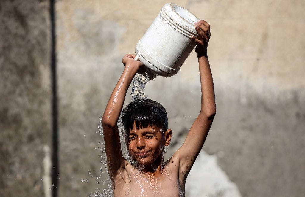 shirtless boy pouring water over himself
