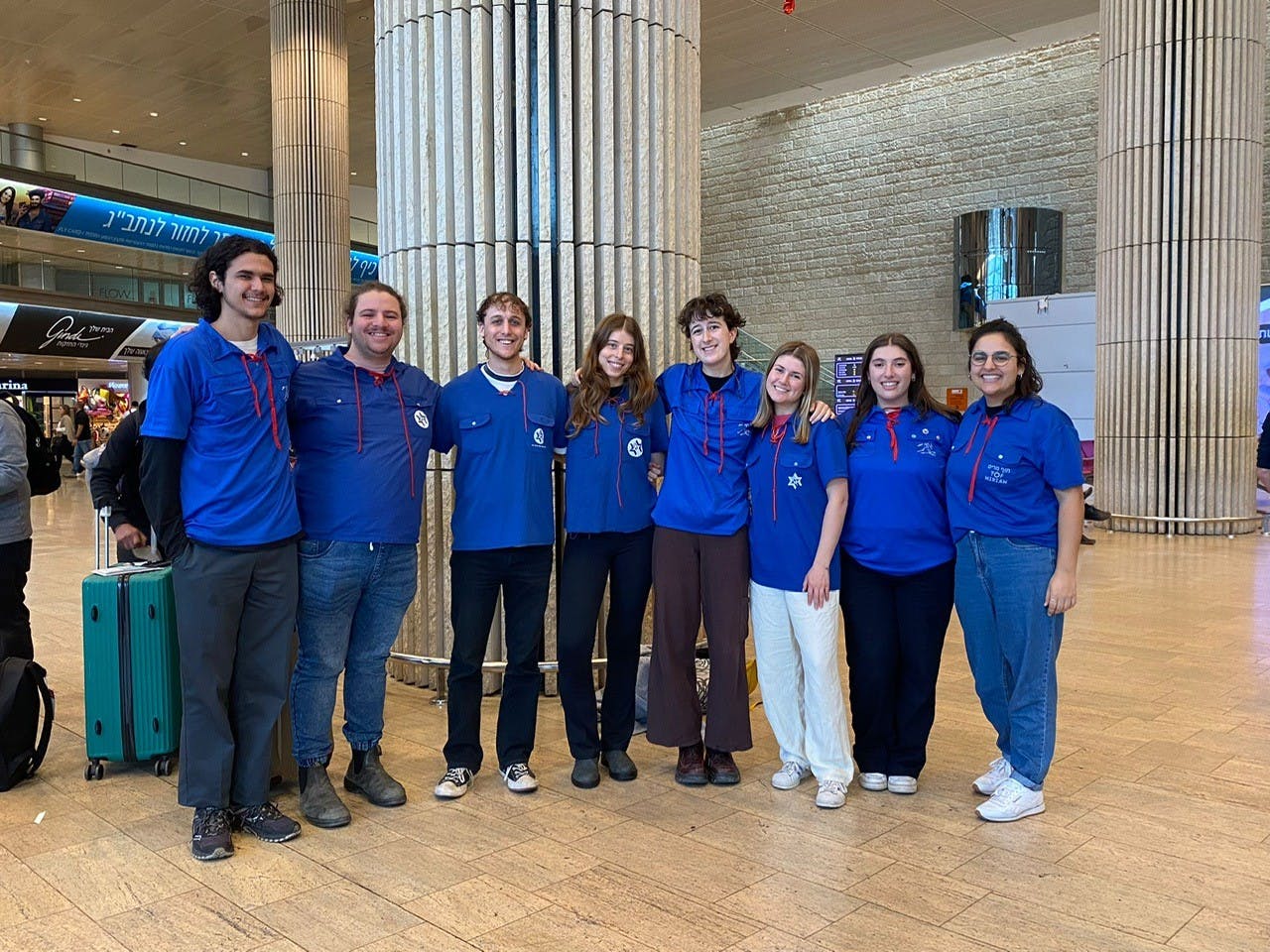Hannah in a blue Habonim Dror top with other people making aliyah at the airport