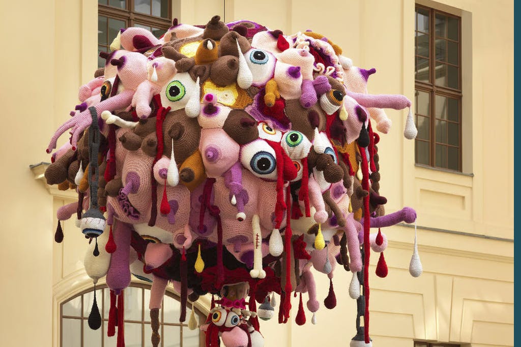 Soft sculpture made of breasts and eyes hanging outside a building