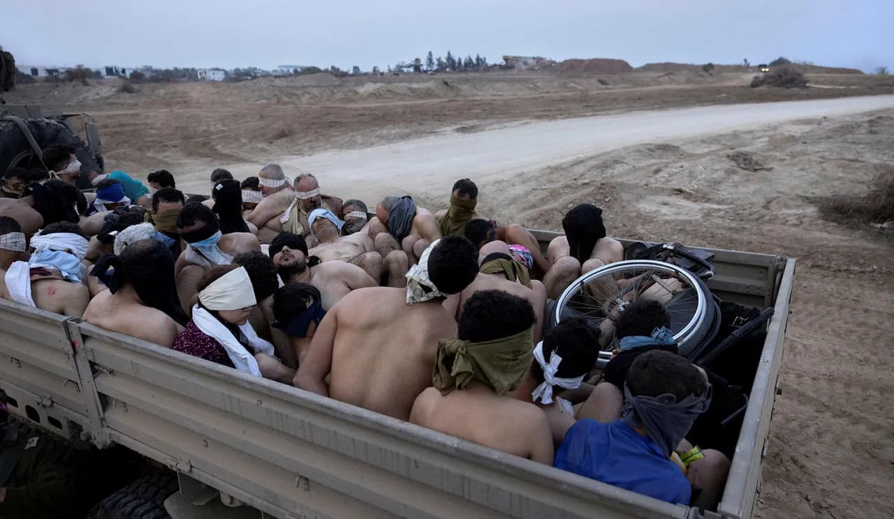 Men, some shirtless, blindfolded in the back of a truck