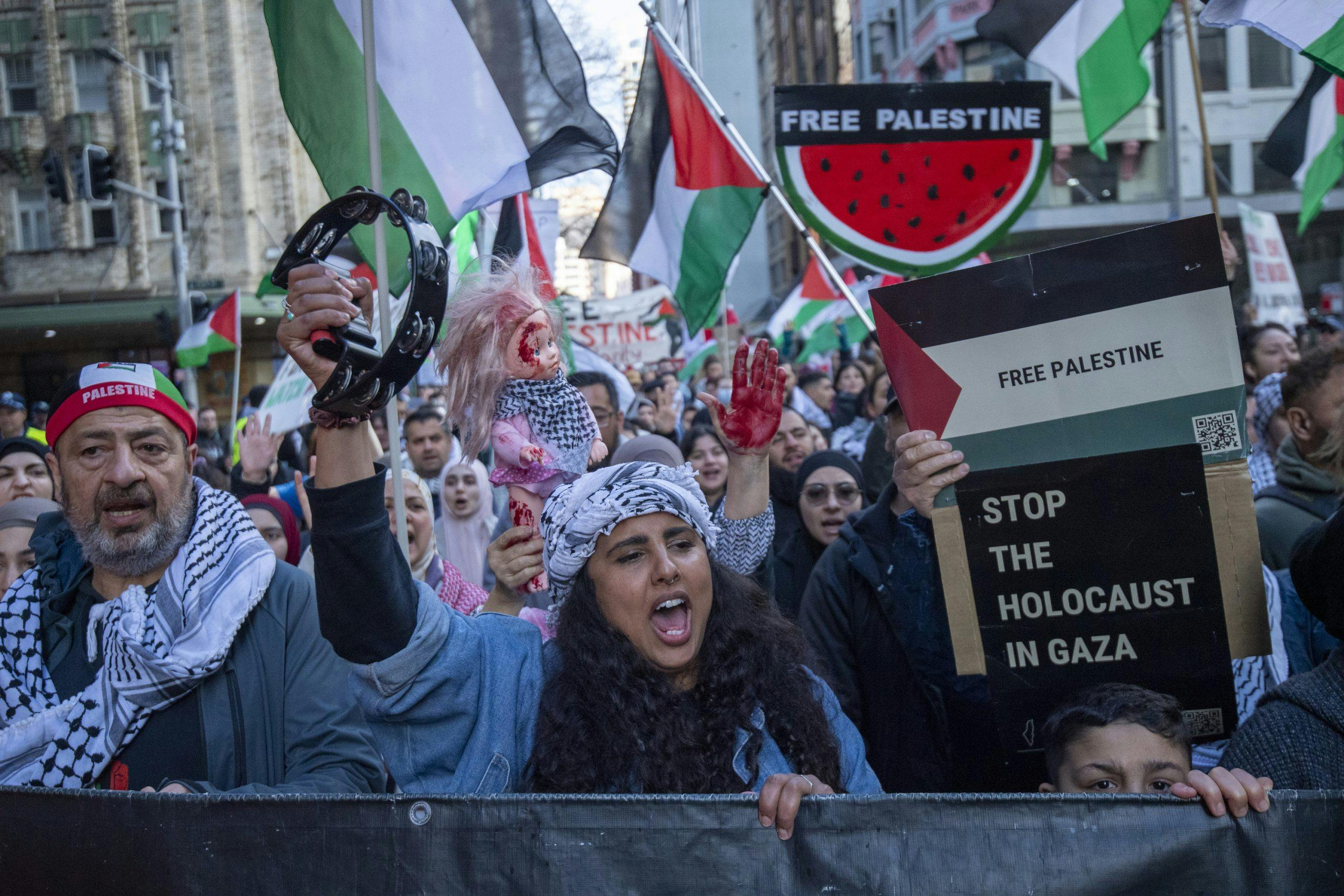 protesters, watermelon signs, Palestinian flags, sign reading 'Stop the Holocaust in Gaza'