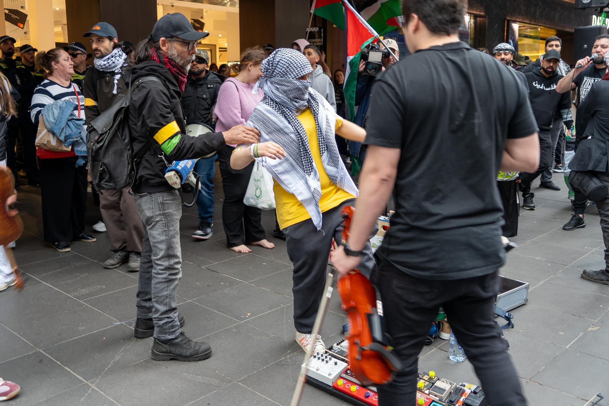 Man wrapped in keffiyah stepping on electronic equipment