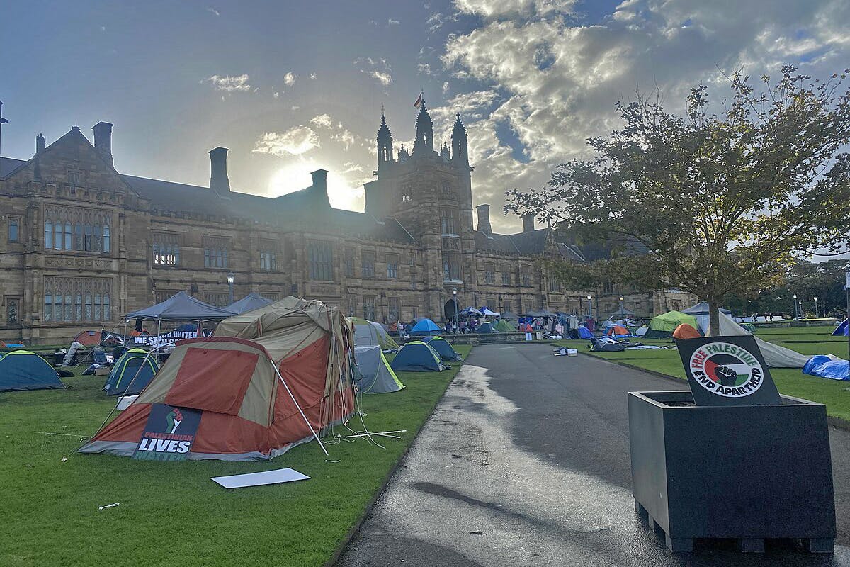 tents in front of Gothic university buildings at dawn