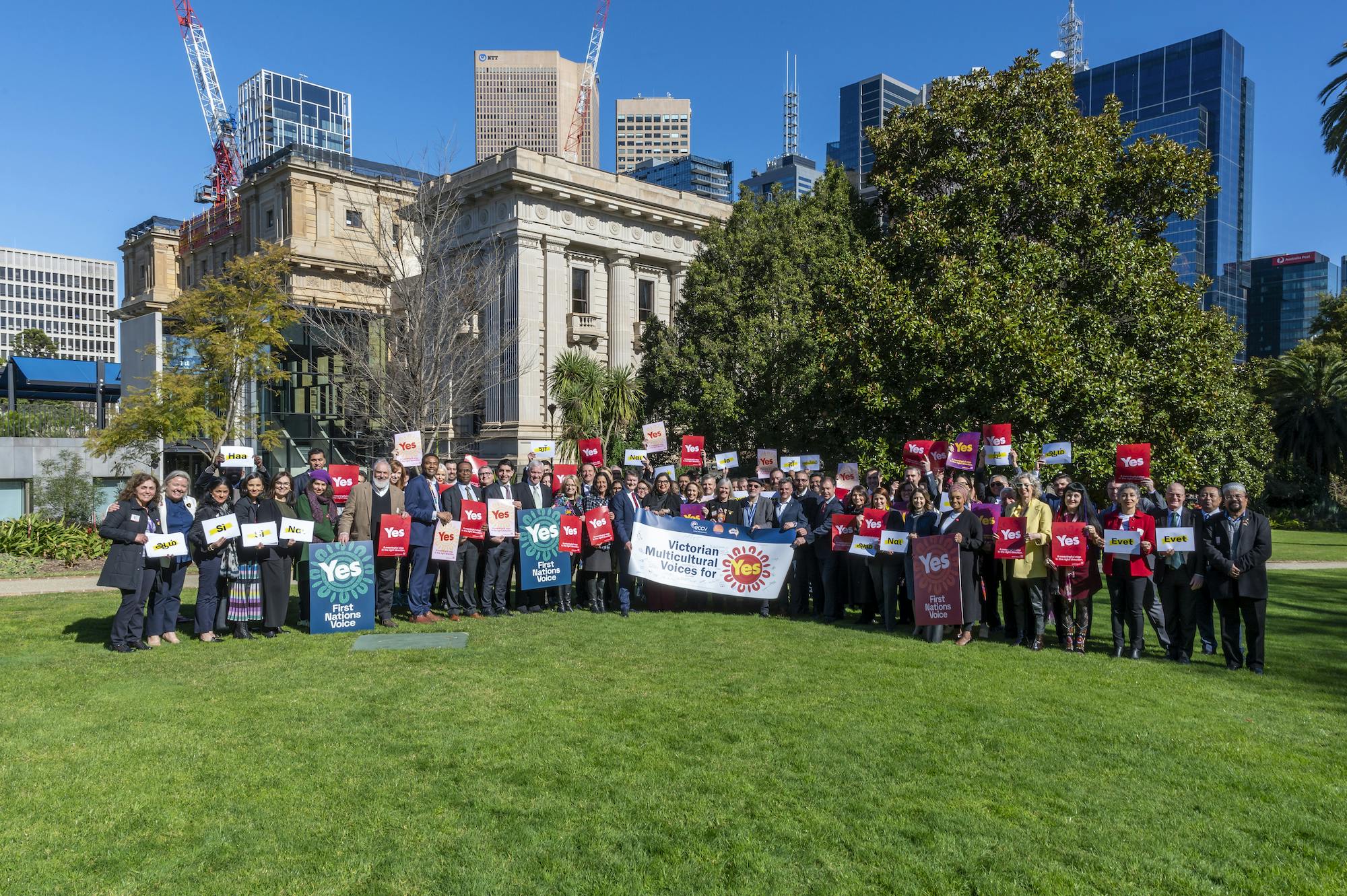 Large gorup of peopl ein front of Victorian parliament with banner resding 'Victorian multicultural voices for yes'