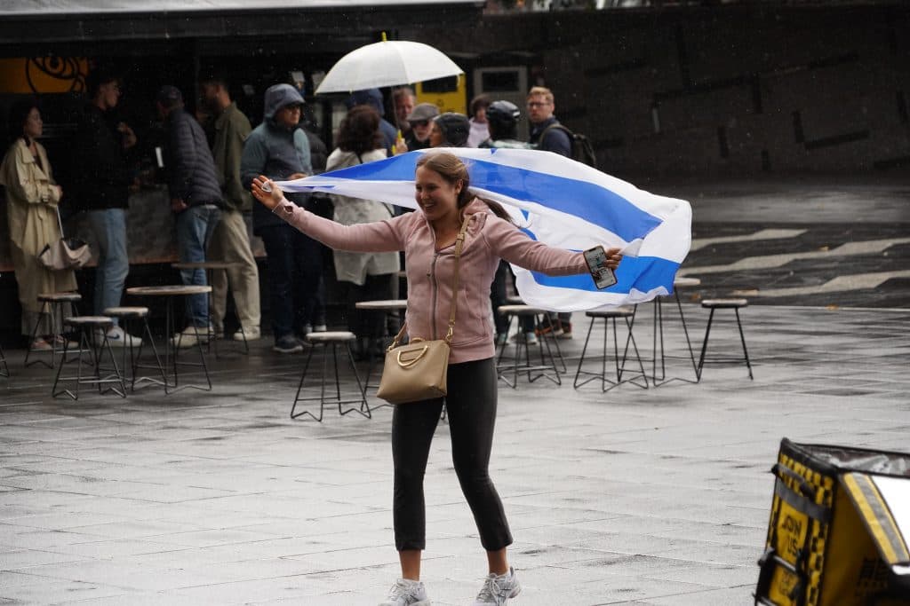 A vigil attendee battles Melbourne weather with her flag (Ben Bresley)