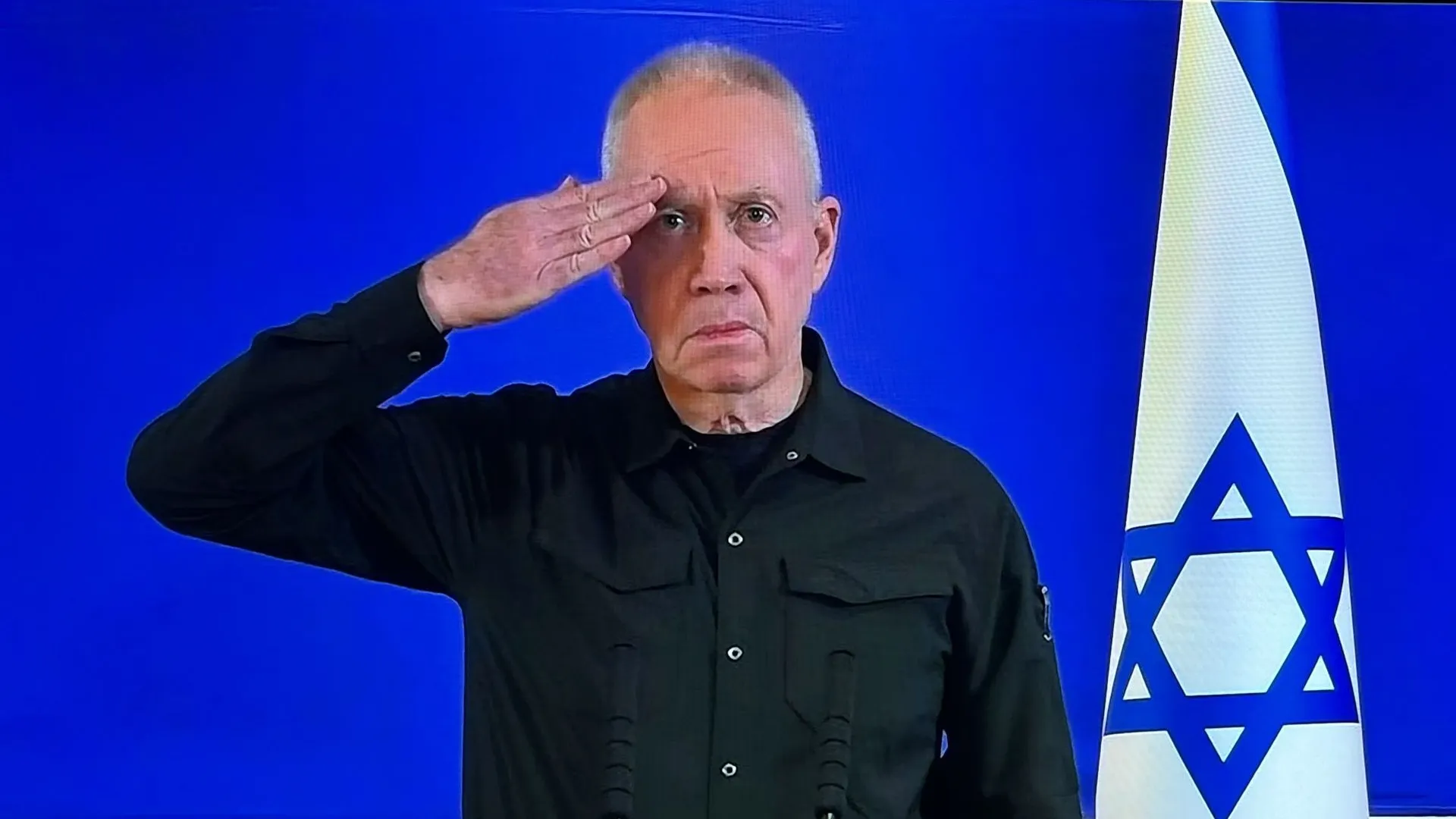 Man standing next to an Israeli flag saluting