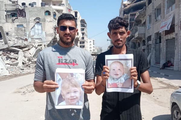Two activists in Gaza holding photos of Israeli children killed